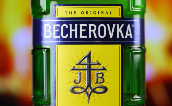 KYIV, UKRAINE – MAY 4, 2022 Becherovka original alcohol bottle on wooden table with red fireplace