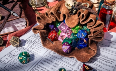 A leather dice bag filled with dice on a character sheet
