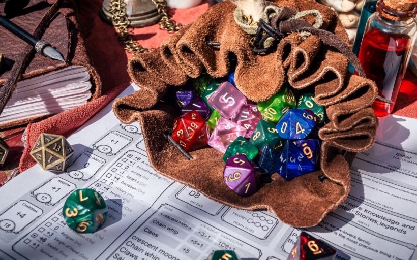 A leather dice bag filled with dice on a character sheet